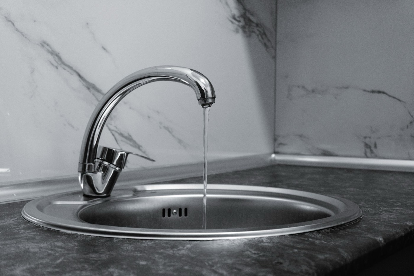 Premium chrome faucet running clean water against marble